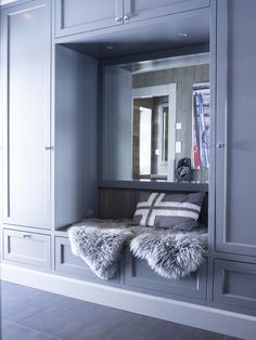 a room with some gray cabinets and pillows on top of each other in front of a mirror