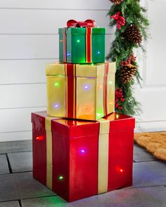 three presents are stacked on top of each other with christmas lights around them and bows