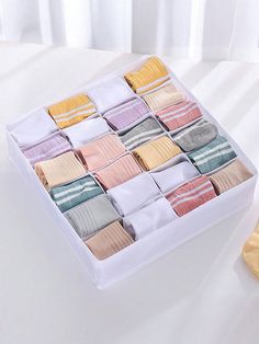 a white box filled with assorted folded towels on top of a bed next to a pair of yellow socks