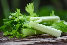 celery stalks and leaves on a piece of wood with green foliage in the background