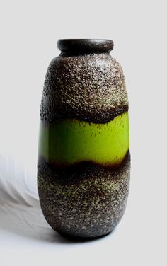 a green vase sitting on top of a white table next to a feather quill