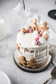 a cake with white frosting and gingerbreads on top sitting on a table