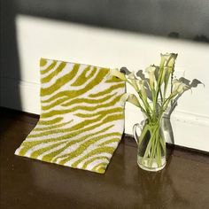 a vase filled with flowers sitting next to a towel on top of a wooden table