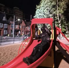 a man sitting on top of a red slide