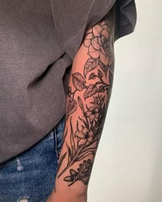 a woman's arm with flowers and leaves on it