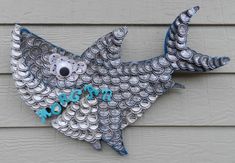 a fish made out of bottle caps on the side of a building