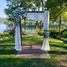 an outdoor wedding ceremony setup with white drapes and blue flowers on the arbors