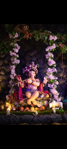 the statue is surrounded by flowers and other things in front of a stone wall with lights on it