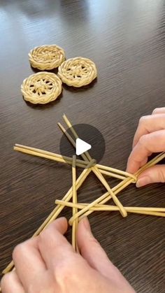 two hands are holding sticks with cookies on the table in front of them and another person is making something out of straws