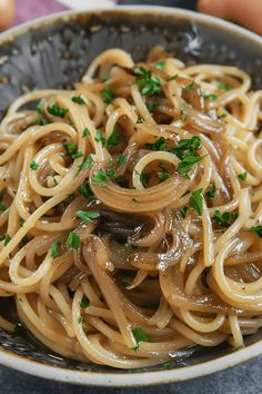 a close up of a bowl of food with noodles and mushrooms in sauce on the side