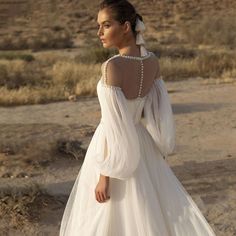 a woman in a wedding dress standing on the desert