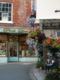 the shop has many flowers growing out of it's windows and on display outside