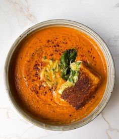 a bowl filled with soup on top of a white table next to a knife and fork