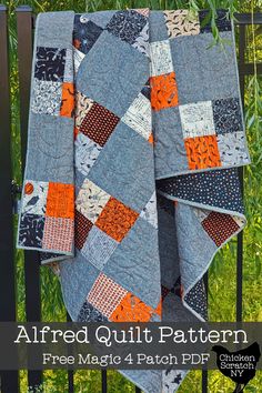 an orange and gray quilt is hanging on a black fence with grass in the background