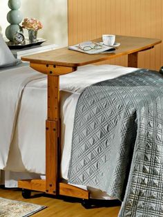 a bed sitting next to a wooden table on top of a hard wood floor