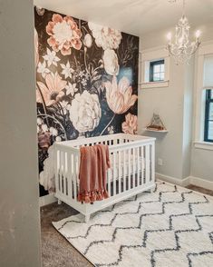 a baby's room with a floral wallpaper and white crib in the corner