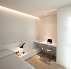 a bedroom with a bed, desk and laptop computer on it's side wall