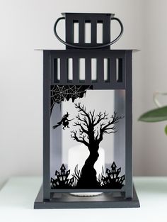 a black lantern with a tree and spider web on it