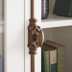 a door handle on the side of a white book shelf next to books and other items