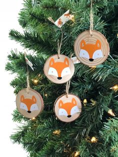 three wooden ornaments hanging from a christmas tree with lights around them and a fox face on the front