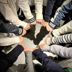 a group of people standing in a circle with their hands on top of each other