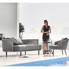 a woman vacuuming the floor next to a swimming pool with chairs and couches