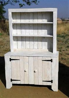 an old white wooden cabinet sitting in the middle of a field