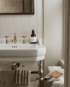 a bathroom sink sitting under a mirror next to a towel rack with bottles on it