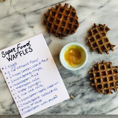 some waffles are sitting on a table next to a small bowl of syrup