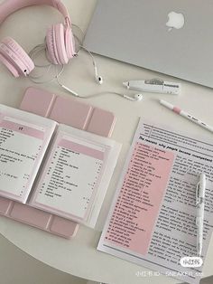 a table with headphones, papers and an apple laptop