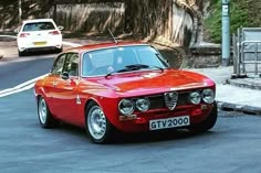 an old red car is driving down the street