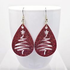 Christmas Tree cutout earrings created with crystal clear epoxy resin and classic Red glitter.  Finished with Stainless Steel fishhook ear wires with silicone backs.  Festive holiday earrings measure 2 3/4 inches long and 1 1/4 inches wide.   Celebrate the holidays in glamorous style with these super sparkly, fun earrings.  Makes the perfect Christmas gift for her, Secret Santa gift and a brilliant gift for you.  Why not treat yourself!?  🎁 Arrives in a gift box with bow, ready for giving. 🎁  📦  All orders are shipped via USPS with tracking. Santa Earrings Diy, Christmas Resin Jewelry, Christmas Leather Earrings, Leather Christmas Earrings, Holiday Party Earrings, Elf Earrings, Jewelry Painting, Tree Cutout, Cricut Jewelry