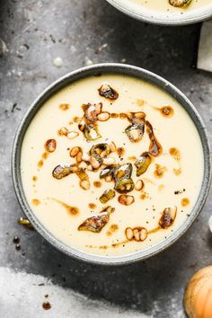 two bowls filled with soup sitting on top of a table next to garlic and mushrooms