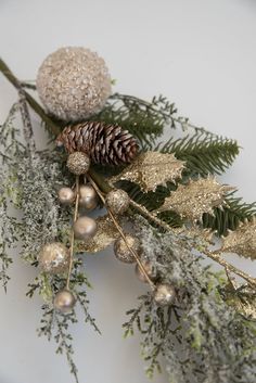 a pine cone is sitting on top of some evergreen branches with balls and glitters