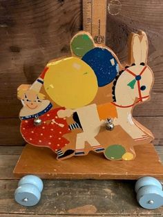 a wooden toy with wheels on it and an animal figurine in the middle