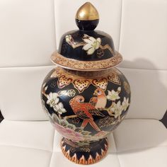 a black and gold urn sitting on top of a white chair