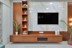 a living room with a large television mounted on the wall and some potted plants in front of it