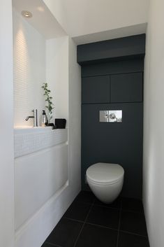 a white toilet sitting inside of a bathroom next to a wall mounted faucet