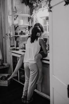 two people standing in front of a kitchen counter talking on the phone and leaning against each other