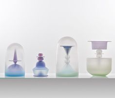 five different colored vases sitting on top of a shelf