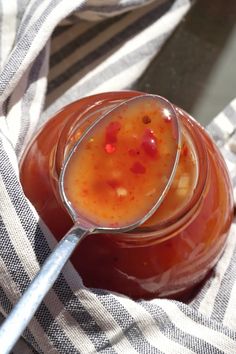 a glass jar filled with liquid sitting on top of a striped cloth next to a spoon