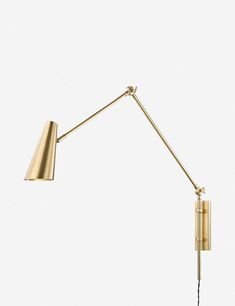 a gold wall lamp with a black cord on the side and a white background behind it