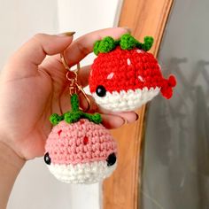 a hand holding two crocheted strawberry keychains