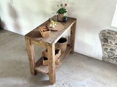 a wooden table with baskets on it in a room next to a stone bench and potted plant