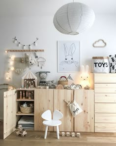 a white room with wooden furniture and decorations on the wall, including a toy chest