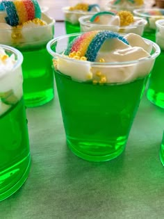 small cups filled with green jello and topped with rainbow decorations on top of a table