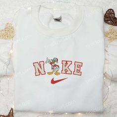 Introducing the Nike Christmas x Donald Duck Embroidered Sweatshirt, a festive masterpiece that combines the iconic charm of Donald Duck with the renowned quality of Nike. This limited edition sweatshirt is adorned with intricate embroidery, showcasing Donald Duck in a jolly Christmas scene. Crafted with premium materials, it offers unparalleled comfort and durability, making it a perfect addition to your holiday wardrobe. Whether you wear it to cozy up by the fireplace or as a statement piece a Custom Made Nike Shirts, Nike Cartoon, Maroon Hoodie, Embroidered Shirts, Best Valentine's Day Gifts, Patrick Star, Hoodie Material, Custom Nikes, Embroidered Clothes