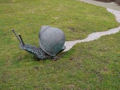 a large metal object sitting on top of a lush green field next to a dirt road