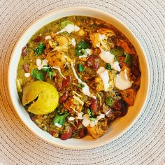 a white bowl filled with lots of food on top of a table next to a napkin