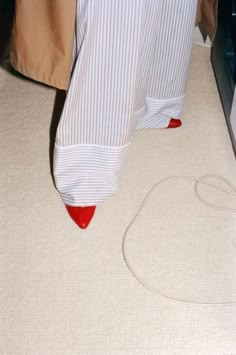 the legs of a person in striped pants and red shoes